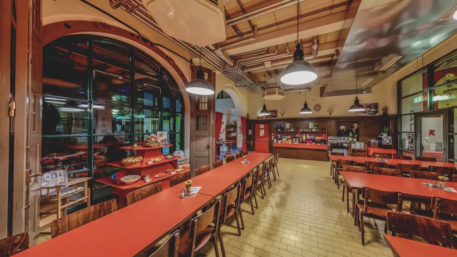 Innenbereich des Restaurants im industriellen Stil mit Holztischen und -stühlen im Jugendgästehaus Plauen