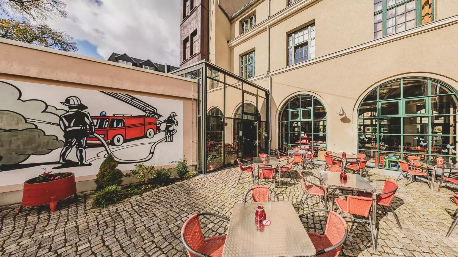 Innenhof des Jugendgästehauses in Plauen mit vielen Tischen und Stühlen zum Verweilen in der Sonne