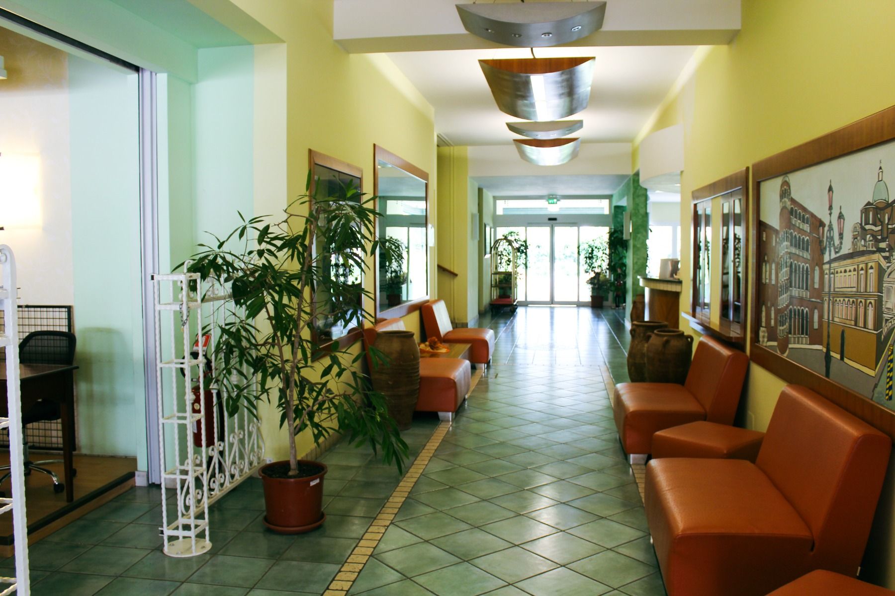 Eingangsbereich im Hotel Pra Delle Torri mit zitronengelben Wänden, Ledersofas und gefliestem Boden