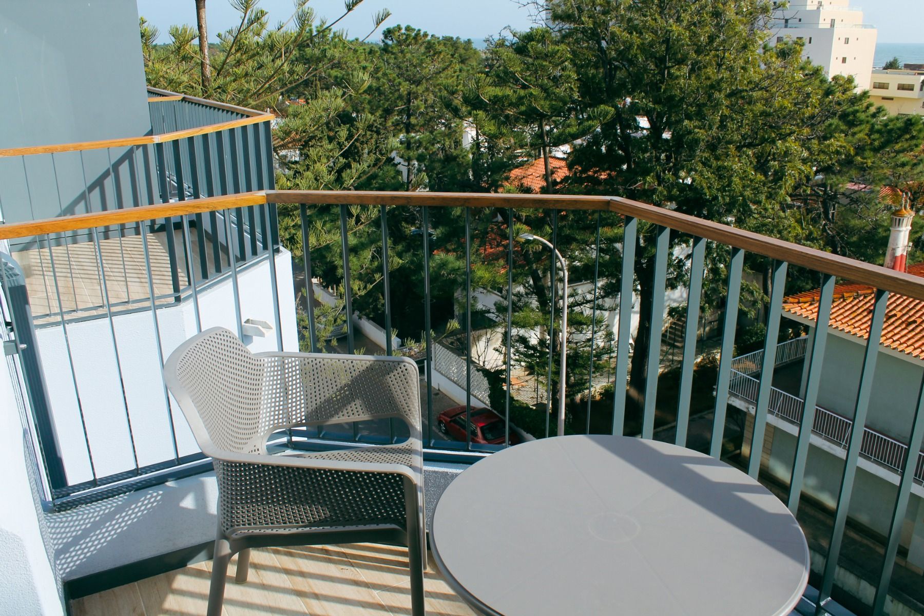 Balkon mit Tisch und Stuhl und Blick auf die umgebenden Bäume und Gebäude.