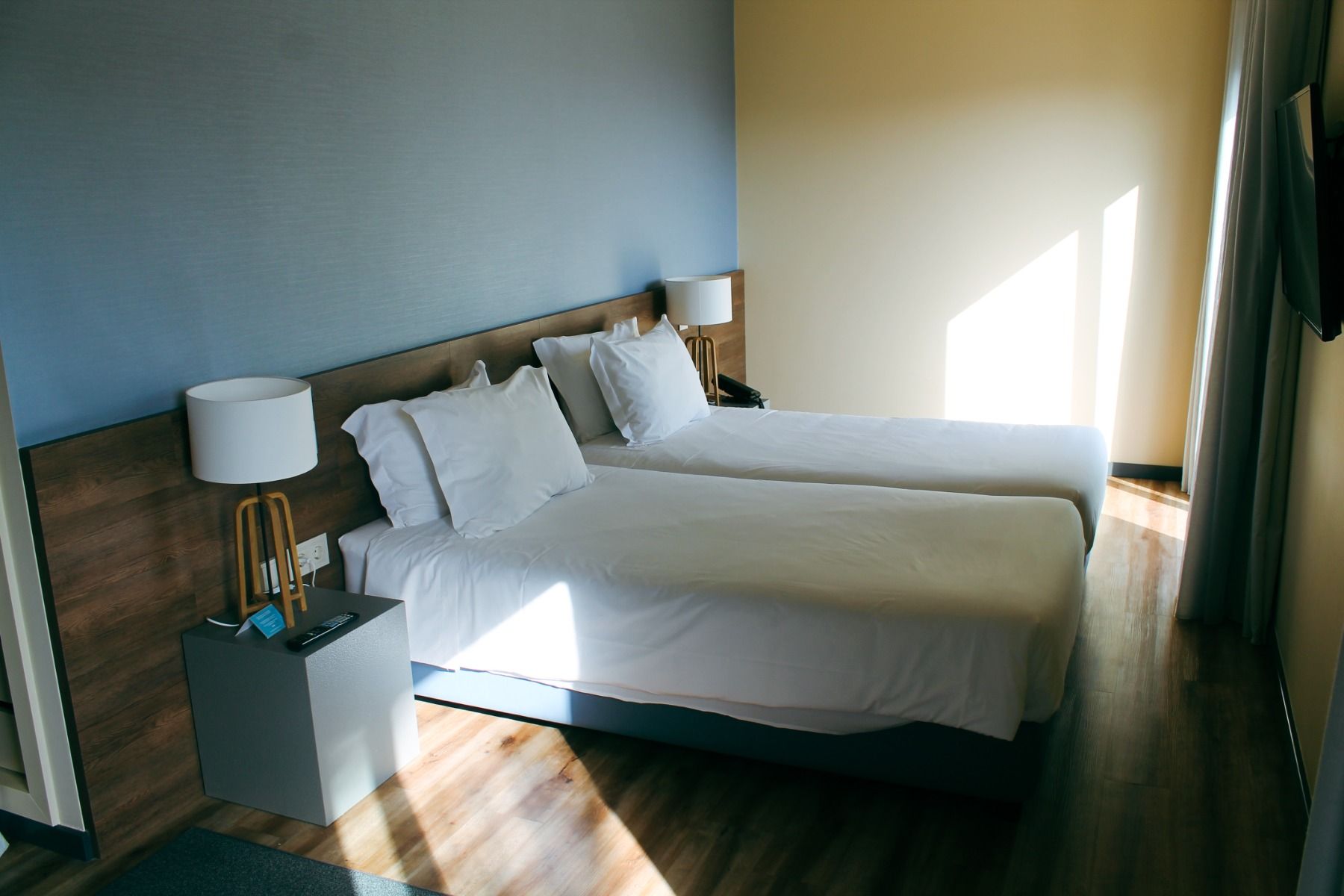 Sonnendurchflutetes Zimmer mit zwei Betten und moderner Einrichtung.