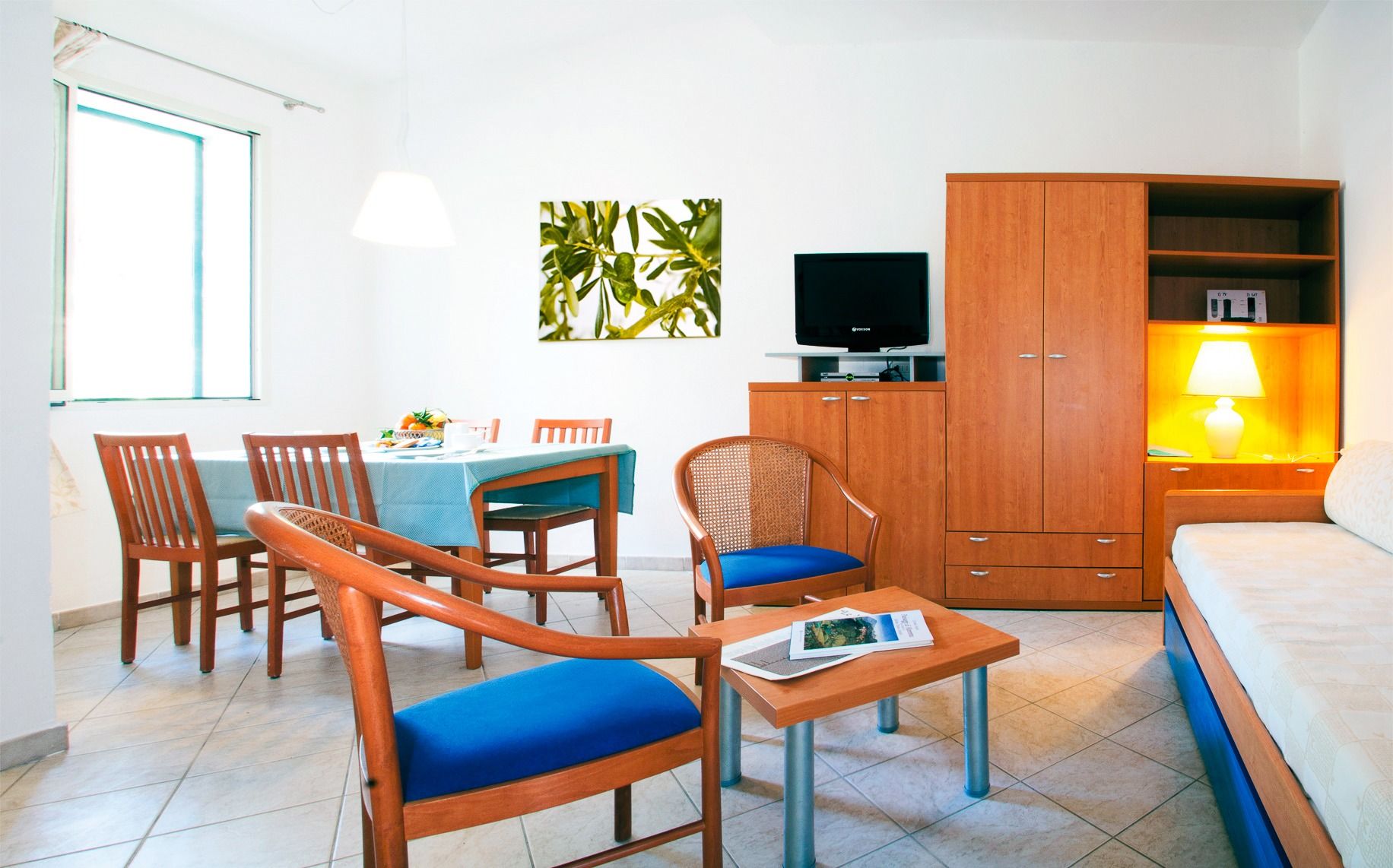 Wohnbereich eines größeren Apartments im Hotel Riva del Sole mit Sofa, Essensbereich und Schränken mit Fernseher