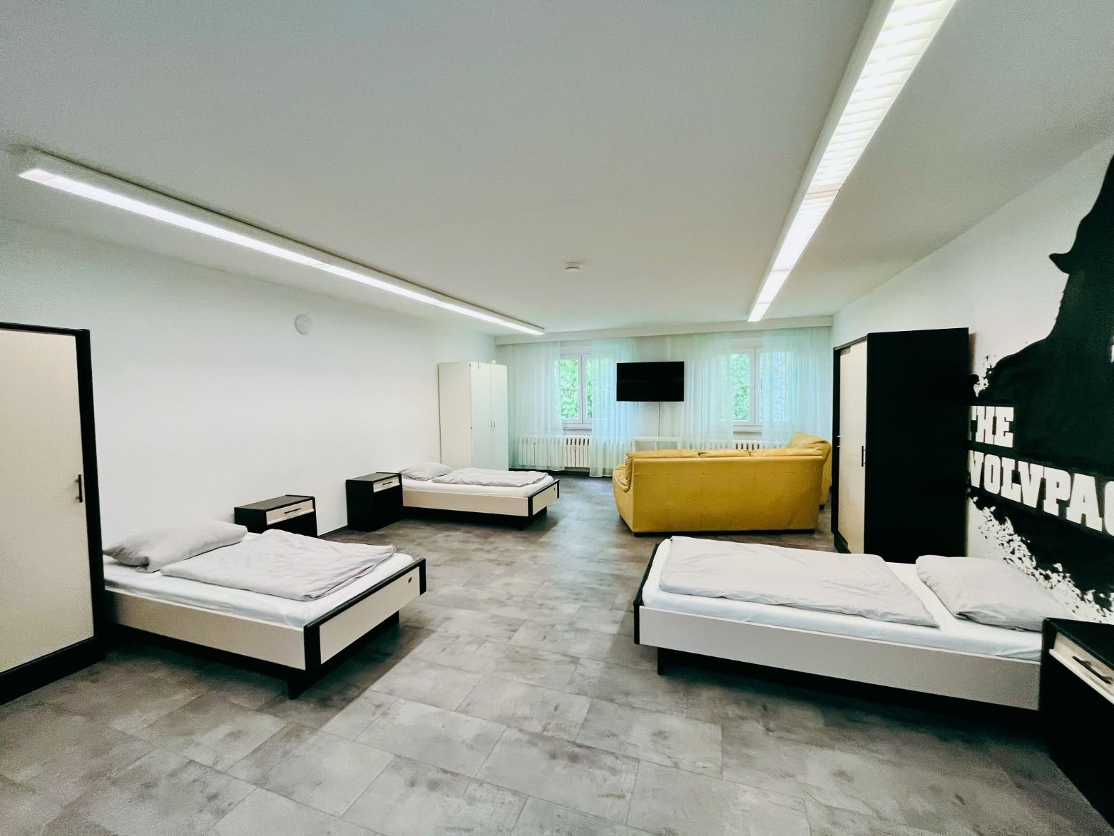 Geräumiges Zimmer mit mehreren Einzelbetten, Couch und Fernseher im Sportcampus Schlotheim