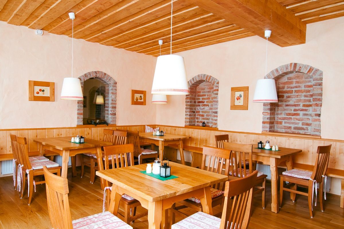 Gemütlicher Speisesaal mit Holzmöbeln, Backsteinakzenten und hängenden Lampen.
