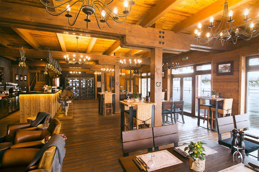 Rustikales Restaurant im Western-Stil mit Holzbalken, Kronleuchtern und gemütlicher Atmosphäre.