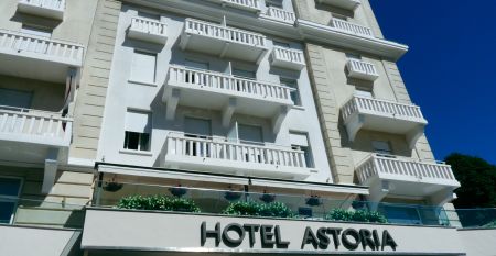 Außenansicht des Hotel Astoria mit weißer Fassade und Balkonen, umgeben von strahlend blauem Himmel