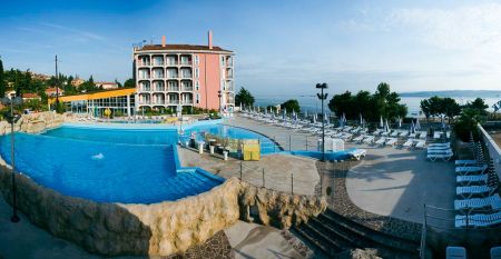 Außenansicht des Hotels Aquapark Zusterna mit rosa Fassade, Balkonen und der slowenischen Flagge.