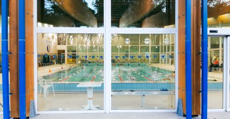 Bunte Fassade der Piscina Olimpica im Bella Italia & EFA Village, umgeben von Pinien und Grünflächen