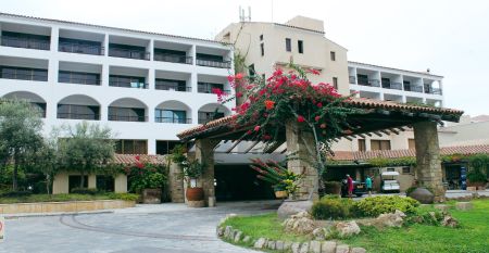 Eleganter Eingangsbereich des Coral Beach Hotel & Resort mit blühenden Bougainvillea und mediterranem Flair.