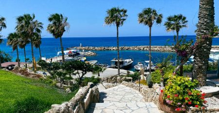 Eleganter Eingangsbereich des Coral Beach Hotel & Resort mit blühenden Bougainvillea und mediterranem Flair.