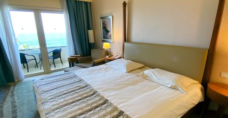 Eleganter Eingangsbereich des Coral Beach Hotel & Resort mit blühenden Bougainvillea und mediterranem Flair.