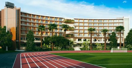 Hotelgebäude mit mehreren Balkonen, neben einer roten Laufbahn und umgeben von Palmen.