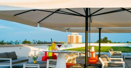 Außenansicht des Hotels Akademia mit gepflegtem Garten und modernen Balkonen. Sonniger Tag und einladende Atmosphäre.