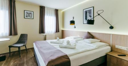 Außenansicht des Hotels Amstel Hattyu Fogado mit moderner Architektur, großen Glasfronten und einer grünen Umgebung