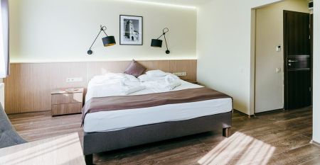 Außenansicht des Hotels Amstel Hattyu Fogado mit moderner Architektur, großen Glasfronten und einer grünen Umgebung