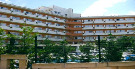 Außenansicht des Hotels Janeiro mit mehrstöckigen Balkonen und gepflegten Pflanzen im Vordergrund.