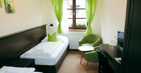Der Empfangsbereich des Hotels Koruna, mit einer hölzernen Rezeption und einer roten Teppichtreppe, die nach oben führt.