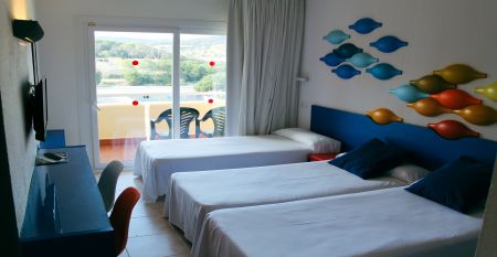 Hotelanlage mit Poollandschaft, Palmen, kleinen Brücken und Blick auf die umliegenden Berge.