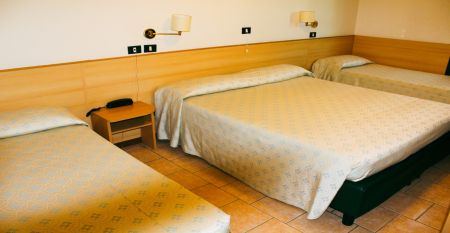 Außenansicht des Hotels Porta Palio mit auffälliger farbenfroher Fassade in Rot, Gelb und Blau, umgeben von Bäumen