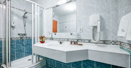 Stilvoll eingerichtetes Hotelzimmer mit einem Doppelbett, blauer Wandtapete und Dachschräge mit Fenster.