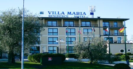 Außenansicht des Hotels Villa Maria mit Balkonen, gepflegtem Garten und mehreren Nationalflaggen vor dem Gebäude