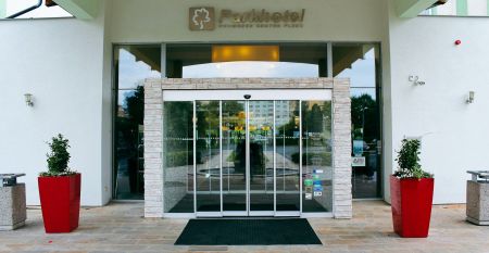 Luftbildaufnahme einer Hotelanlage mit Tennisplätzen, Pool und Parkflächen.