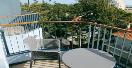 Außenansicht eines modernen Hotelgebäudes mit Balkonen und einem begrünten Vorgarten.