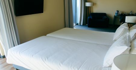Außenansicht eines modernen Hotelgebäudes mit Balkonen und einem begrünten Vorgarten.
