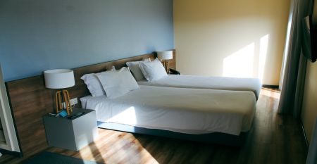 Außenansicht eines modernen Hotelgebäudes mit Balkonen und einem begrünten Vorgarten.