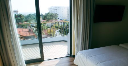Außenansicht eines modernen Hotelgebäudes mit Balkonen und einem begrünten Vorgarten.