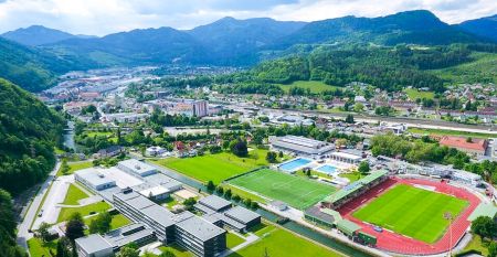 Außenansicht des Sporthotel Kapfenberg mit moderner Fassade und Hotelbeschriftung, im Hintergrund eine Burg auf einem Hügel