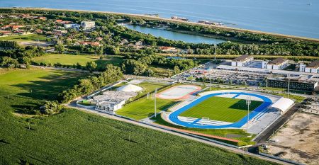 Luftaufnahme des X-Bionic Sportkomplexes mit Schwimmbad, Reitanlage, Leichtathletikstadion und Sportplätzen in grüner Landschaft.