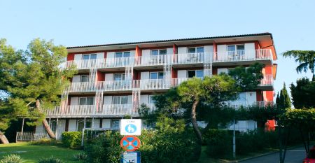 Außenansicht des gelben Gebäudes des Hotels San Simon Dependance, umgeben von Bäumen und Sträuchern.