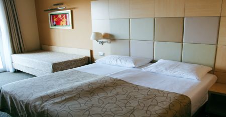 Außenansicht des gelben Gebäudes des Hotels San Simon Dependance, umgeben von Bäumen und Sträuchern.