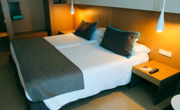 Außenansicht des Hotels mit Balkonen und einem großzügigen Poolbereich mit Liegestühlen und Holzboden.