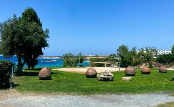 Eleganter Eingangsbereich des Coral Beach Hotel & Resort mit blühenden Bougainvillea und mediterranem Flair.