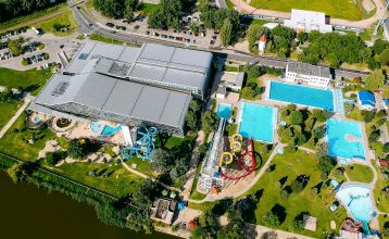 Übersicht des Hotels aus der Vogelperspektive. Das Hotel ist umgeben von Außenpools, Wasserrutschen und gepflegten Grünflächen.