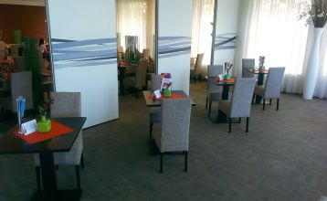 Doppelzimmer im Hotel mit zwei Betten, einem modernen Holzschreibtisch und einem farbenfrohen Wandbild.