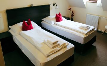 Der Empfangsbereich des Hotels Koruna, mit einer hölzernen Rezeption und einer roten Teppichtreppe, die nach oben führt.