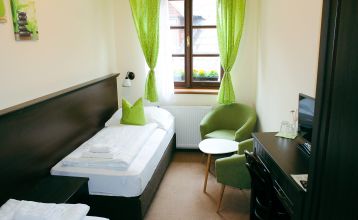 Der Empfangsbereich des Hotels Koruna, mit einer hölzernen Rezeption und einer roten Teppichtreppe, die nach oben führt.
