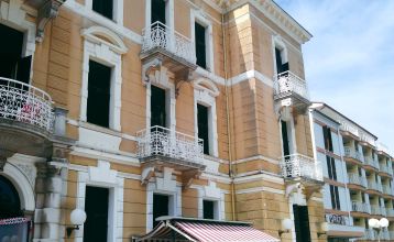 Historische Gebäudeansicht des Hotels Opatija mit dekorativen Balkonen und weißen Fenstern auf gelber Außenfassade
