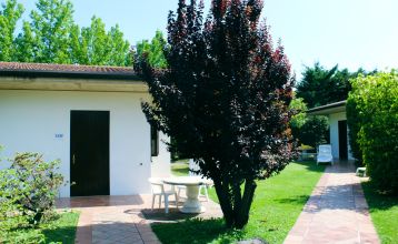 Außenansicht des Hotels Villa Maria mit Balkonen, gepflegtem Garten und mehreren Nationalflaggen vor dem Gebäude