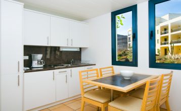 Outdoor-Fitnesskurs mit einer Gruppe von Menschen, die gemeinsam auf Steppern trainieren, vor der Kulisse einer weißen, terrassenförmigen Hotelanlage.