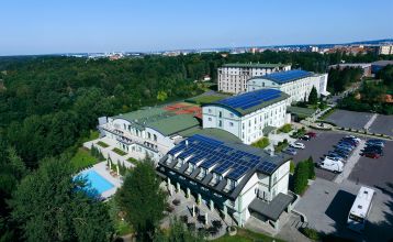 Luftbildaufnahme einer Hotelanlage mit Tennisplätzen, Pool und Parkflächen.
