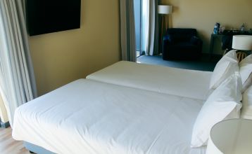 Außenansicht eines modernen Hotelgebäudes mit Balkonen und einem begrünten Vorgarten.