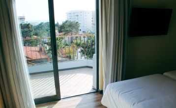 Außenansicht eines modernen Hotelgebäudes mit Balkonen und einem begrünten Vorgarten.