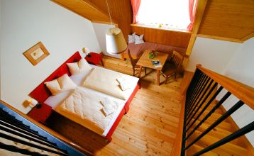 JUFA Tieschen Hotel, umgeben von grünen Feldern und bewaldeten Hügeln, mit traditioneller Architektur und roten Dächern.